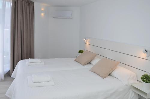 ein Schlafzimmer mit zwei Betten mit weißen Laken und Kissen in der Unterkunft Canary Lofts Glorieta in Santa Cruz de Tenerife