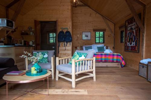 Zimmer mit einem Bett und Stühlen in einer Hütte in der Unterkunft Cabane de La Mésange in Auriac-du-Périgord