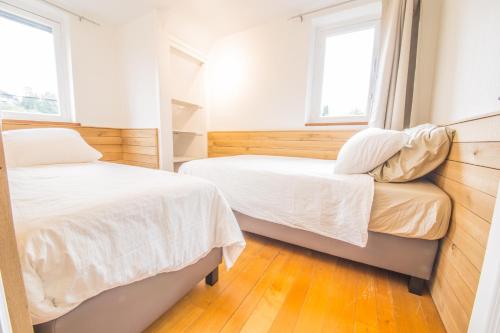 Dos camas en una habitación con dos ventanas. en La Maison du Verger, en Durbuy