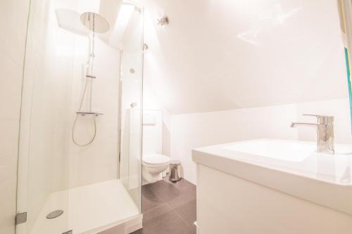 Un baño blanco con lavabo e inodoro. en La Maison du Verger, en Durbuy