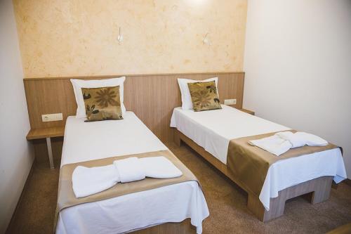 a room with two beds with white sheets at Стаи за гост Хит Хаус и СПА in Bratsigovo