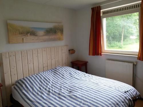 a bedroom with a bed with a striped bedspread and a window at Kijkduinvilla in The Hague