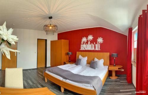 プットブスにあるHotel & Restaurant Am Boddenの赤い壁のベッドルーム1室(大型ベッド1台付)