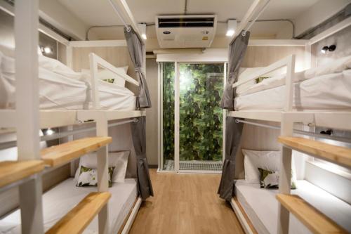 バンコクにあるSiam Eco Hostelの二段ベッドと窓が備わる客室です。