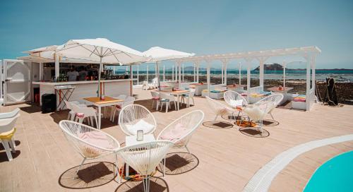 a deck with chairs and tables and a bar on the beach at Apartamentos Punta Elena Beach in Corralejo