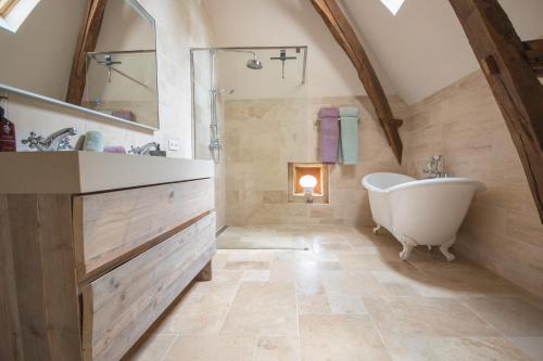 an attic bathroom with a tub and a sink at Maison du Cèdre in Auriac-du-Périgord