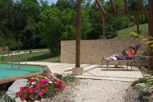 une personne assise sur un banc à côté d'une piscine dans l'établissement Maison du Cèdre, à Auriac-du-Périgord