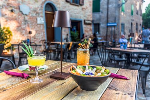 a wooden table with a bowl of food and a drink at Malatesta Antica Dimora in Longiano