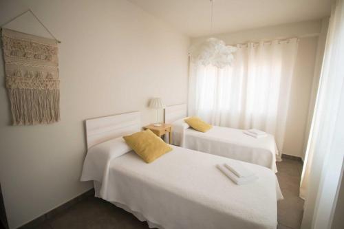 a bedroom with two beds with white sheets and yellow pillows at Apartmento Obispo Rocamora in Orihuela
