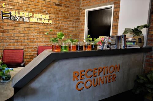 a reception counter with glasses on top of it at Sleep Here Hostel, Melaka in Melaka