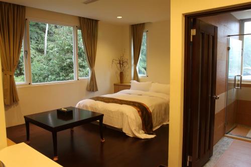a bedroom with a bed and a table and windows at Sun Moon Lake Karuizawa Villa in Yuchi