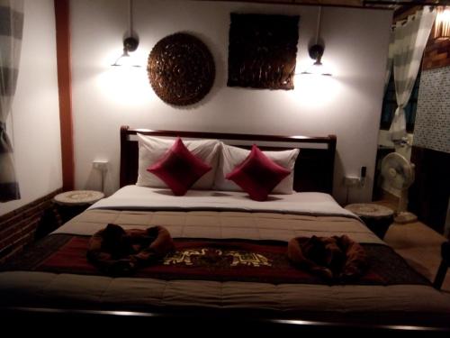 a bedroom with a large bed with red pillows at Hotel Khaosok and Spa in Khao Sok