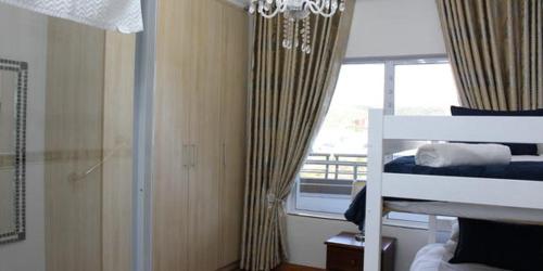 a bedroom with a bed and a window with a chandelier at Vista Bonita Apartments in Mossel Bay