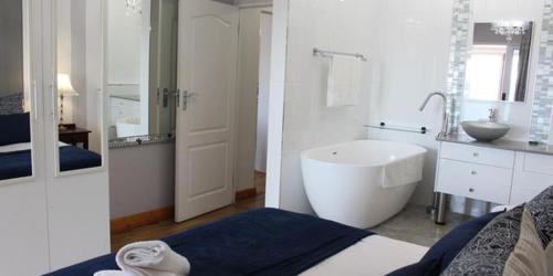 a white bathroom with a tub and a sink at Vista Bonita Apartments in Mossel Bay