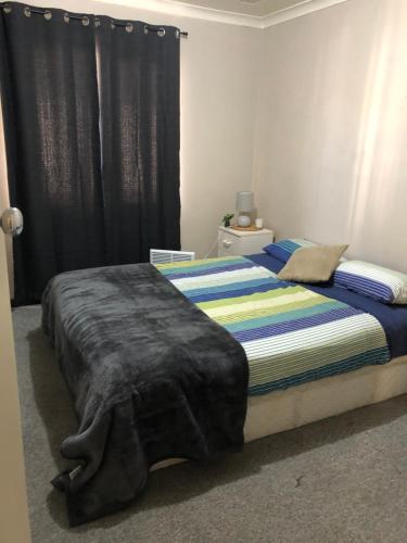 Un dormitorio con una cama con una manta. en Home away from home, en Merredin