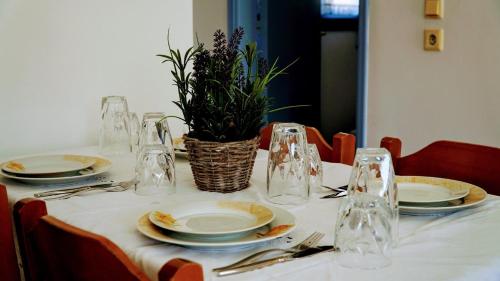 a table with plates and glasses and a plant on it at Irene Family Apartment in Symi