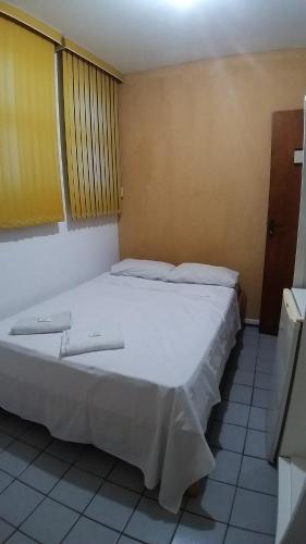 a bedroom with a large white bed in a room at Hotel Donna Linda in Londrina