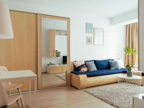 ein Wohnzimmer mit einem blauen Sofa und einem Spiegel in der Unterkunft Comfy Apartment Matei Basarab in Bukarest