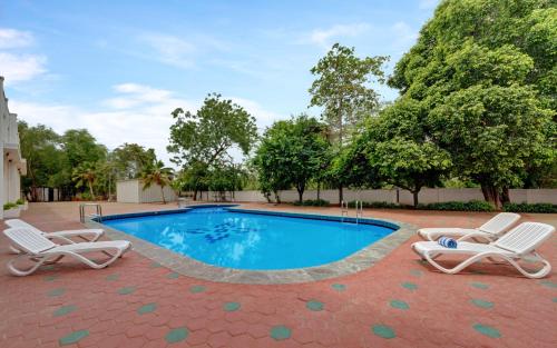 a swimming pool with two lawn chairs and a pair at SRM Hotel Trichy in Tiruchirappalli