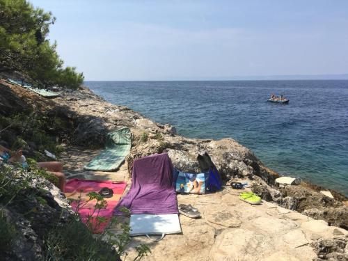 a group of people sitting on the rocks near the water at THE VIEW **** in Račišće