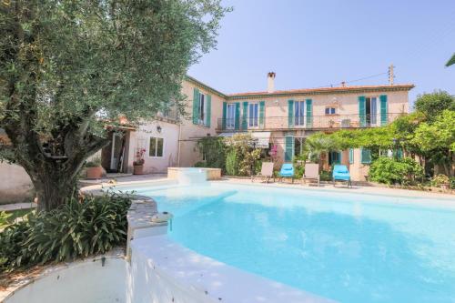 une piscine avec un arbre et un bâtiment dans l'établissement Vencianne, à Vence