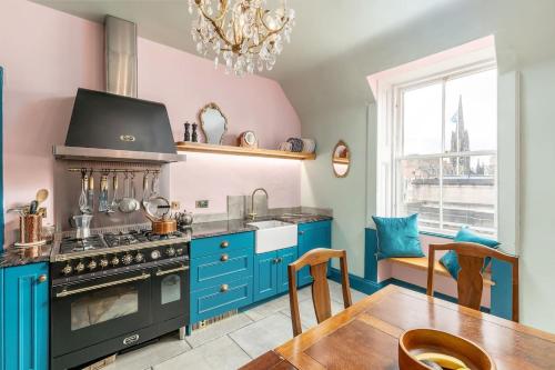 a kitchen with blue cabinets and a stove and a table at JOIVY Luxury Old Town Apartment in Edinburgh
