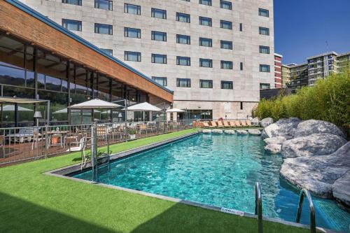 a large swimming pool in front of a building at Hotel Puerta de Bilbao in Barakaldo