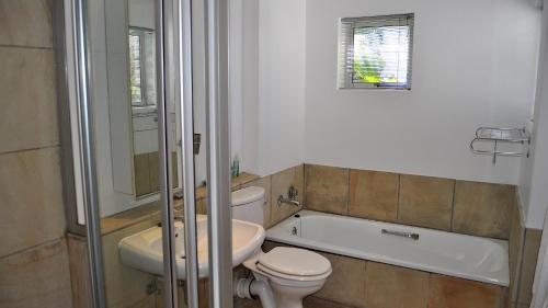 a bathroom with a toilet and a sink and a bath tub at Beachy Head 61 in Plettenberg Bay
