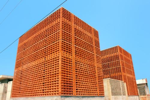 a tall red brick building with at Sengal Boutique Hotel in Auroville