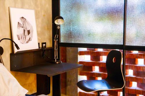 a desk with a lamp and a chair next to a window at Sengal Boutique Hotel in Auroville