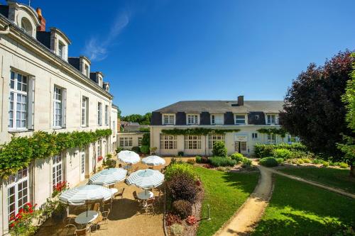 a garden with tables and umbrellas in front of a building at Hôtel Miléade Le Domaine de la Blairie - Saumur in Saint-Martin-de-la-Place