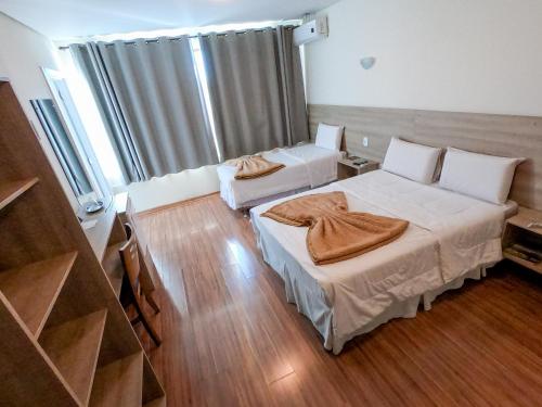 two beds in a room with wooden floors at Dalle Hotel in Bagé