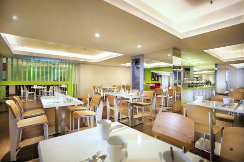 a dining room with tables and chairs in a restaurant at favehotel Gatot Subroto Jakarta in Jakarta