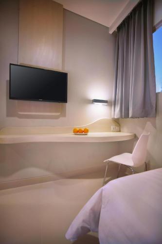 a bedroom with a bed and a tv on a wall at favehotel Gatot Subroto Jakarta in Jakarta