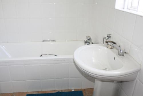 a white bathroom with a sink and a bath tub at Back-Up Power with Stable WiFi! Central in Walmer in Port Elizabeth
