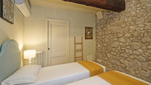 a bedroom with two beds and a stone wall at Dogoli Country Apartments in Bardolino