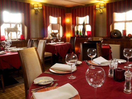 een restaurant met rode tafels en stoelen met wijnglazen bij The Blue Bell Inn in Weaverthorpe