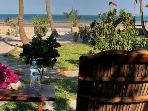 a table with a bottle of water and flowers on the beach at Vilancool Beach Resort in Vilanculos