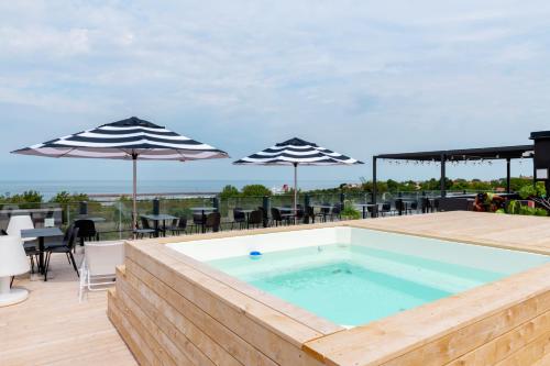 a swimming pool on a deck with umbrellas at First Hotel Kokoloko in Visby