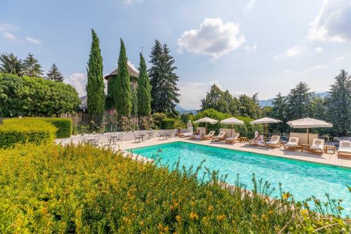 a pool with chairs and umbrellas in a yard at Château de Candie in Chambéry