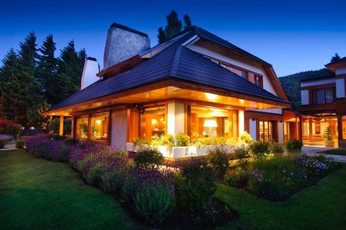 a house with a garden in front of it at Hostería Antares Patagonia by Visionnaire in San Martín de los Andes
