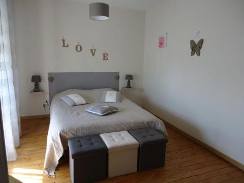 ein Schlafzimmer mit einem Bett mit zwei Hockern in der Unterkunft Chambres d'hôtes à CUILLÉ in Cuillé