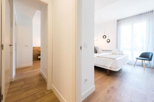 a white bedroom with a bed and a chair at Plaza de España Skyline in Madrid
