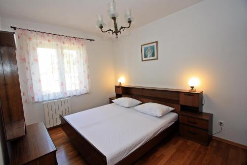 una camera da letto con un letto con lenzuola bianche e una finestra di Apartment Igor a Supetar (San Pietro di Brazza)