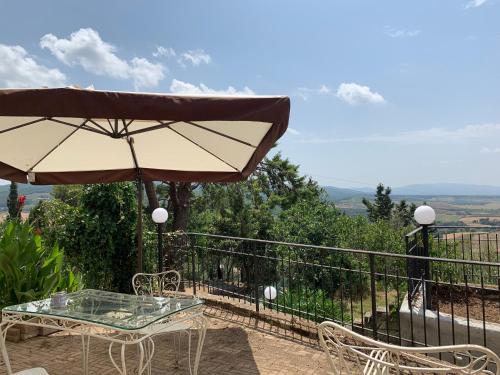 a table and chairs with an umbrella on a balcony at Casa Cerboneschi in Casale Marittimo