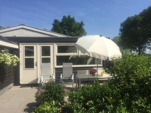a house with a table and an umbrella at Lekerweg 32 in Wijdenes