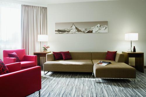 a living room with a couch and a red chair at Mövenpick Hotel Geneva in Geneva