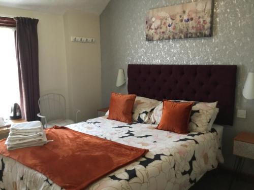 a bedroom with a large bed with orange pillows at Kirkstall Guest House in Blackpool