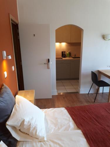 a bedroom with a bed and a table and a kitchen at Guesthouse Dusart in Hasselt