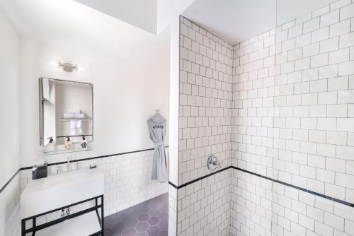 a white tiled bathroom with a sink and a mirror at The State Hotel in Seattle